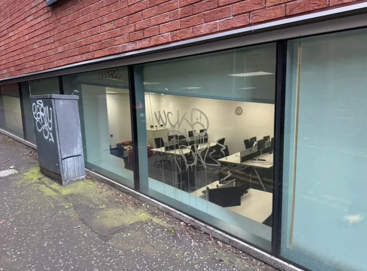 Acid-etched graffiti on commercial office glazing in Glasgow, before restoration