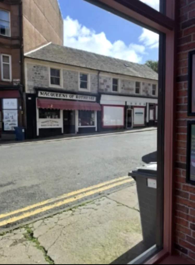 Restored bookshop shopfront glass in Rothesay viewed from inside, giving a clear view across the street