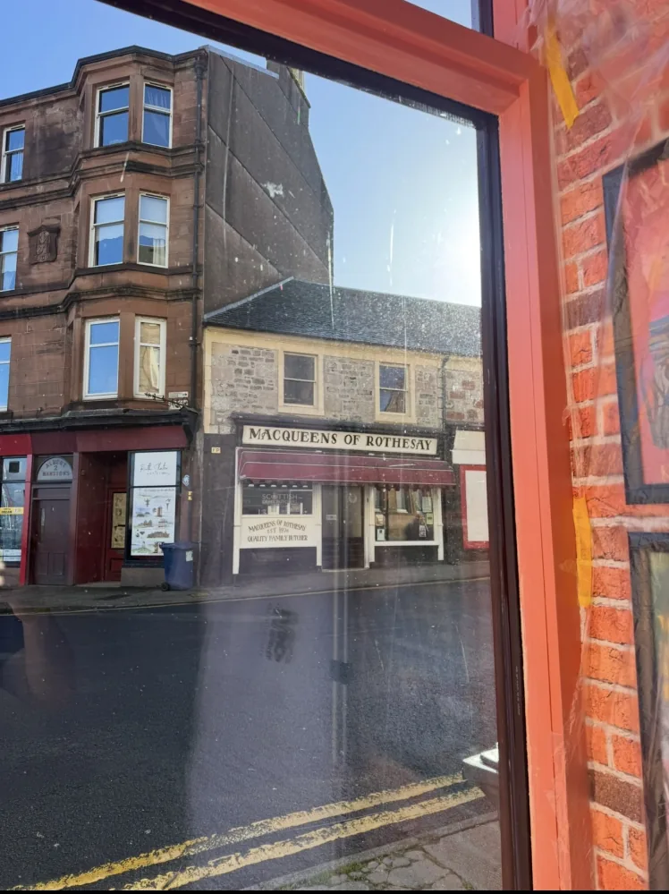 Scratched shopfront glass viewed from inside a bookshop in Rothesay, Isle of Bute, before restoration
