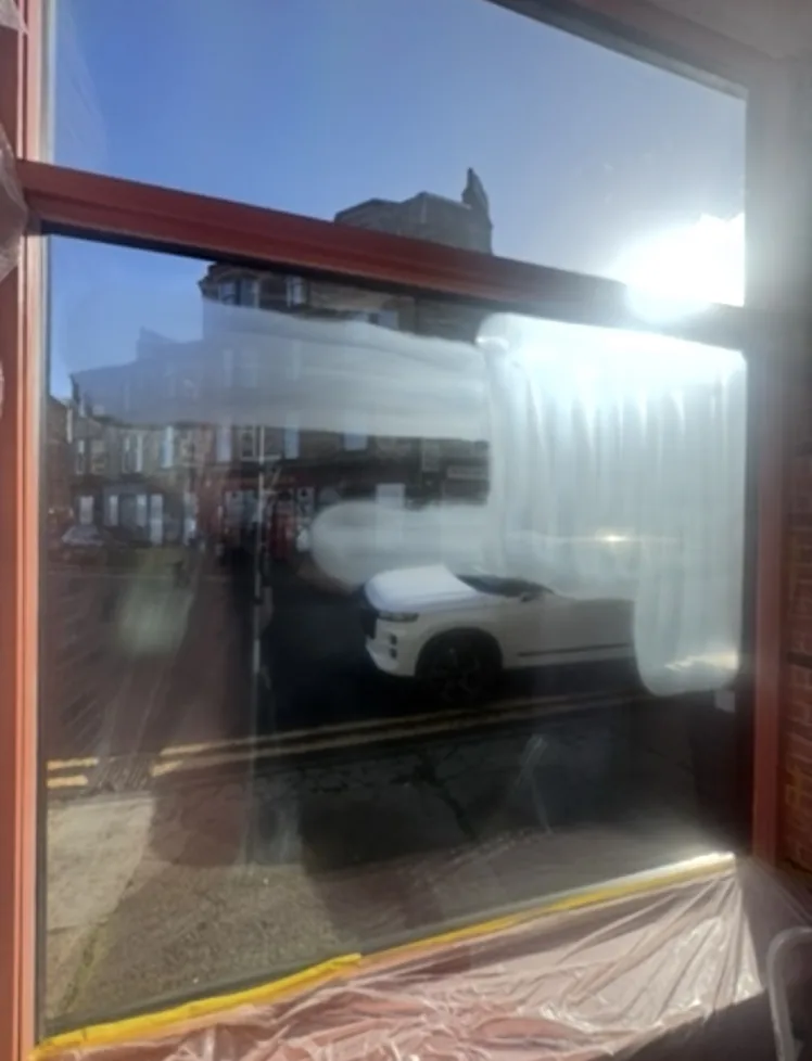 Bookshop glazing in Rothesay viewed from inside during restoration, showing temporary surface haze and treatment marks