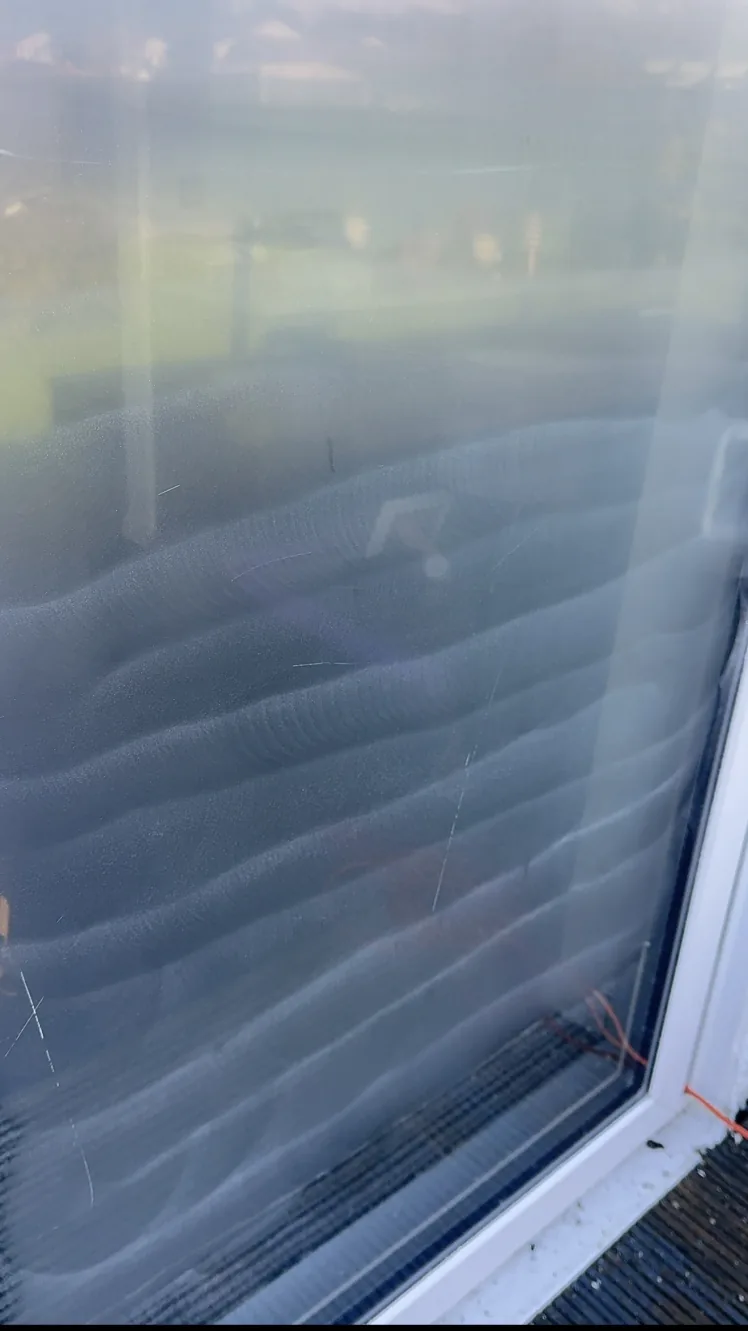 Close-up of patio door glass in St Andrews during surface preparation, with scratches still visible on the partially ground surface