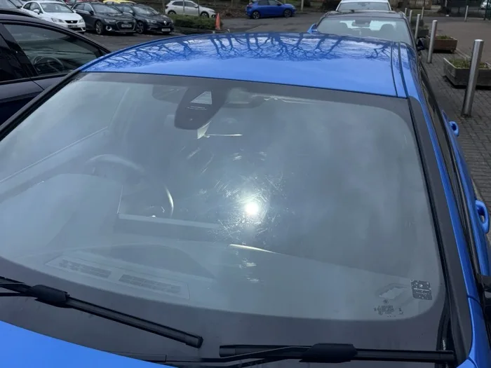 Windscreen with full-surface wear and scratching around sun glare before restoration